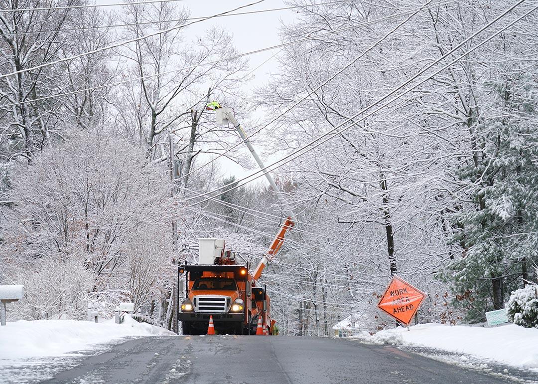 crews in bucket truck working on power lines in snowy condition