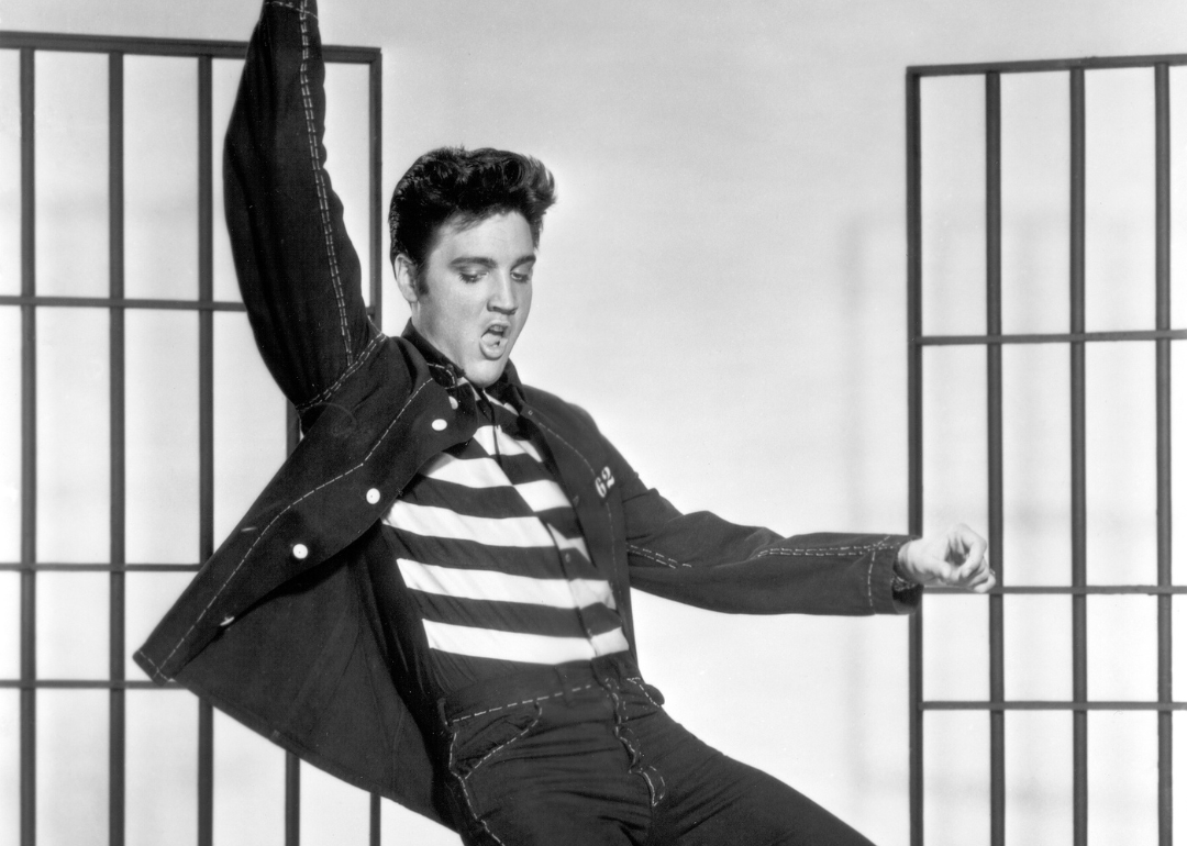  American actor and singer Elvis Presley (1935 - 1977) dancing in a stylized prison uniform in a promotional portrait for director Richard Thorpe's film, 'Jailhouse Rock.'