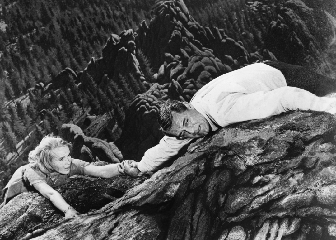 Roger O Thornhill, played by Cary Grant (1904 - 1986), and Eve Kendall, played by Eva Marie Saint, hanging from a cliff at Mount Rushmore in 'North By Northwest', directed by Alfred Hitchcock, 1959.