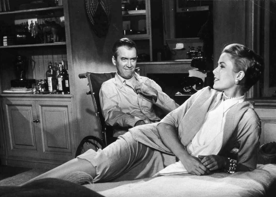Grace Kelly (1929 - 1982) reclines on a bed while actor James Stewart (1908 - 1997) smiles at her from a wheelchair in a still from director Alfred Hitchcock's film, 'Rear Window,' 1954.
