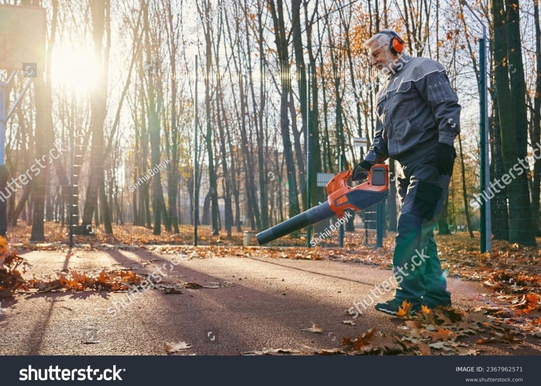 man using leafblower in forest while sun sets behind