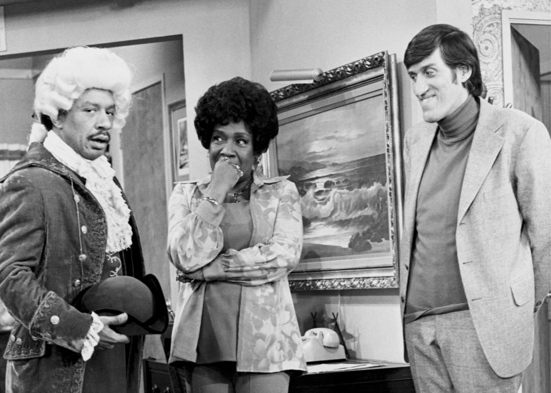Isabel Sanford, as Louise, inspects an oddly dressed Sherman Hemsley (left), as George, while Paul Benedict, as Harry Bentley, looks on, in the second-season premiere episode of 'The Jeffersons'