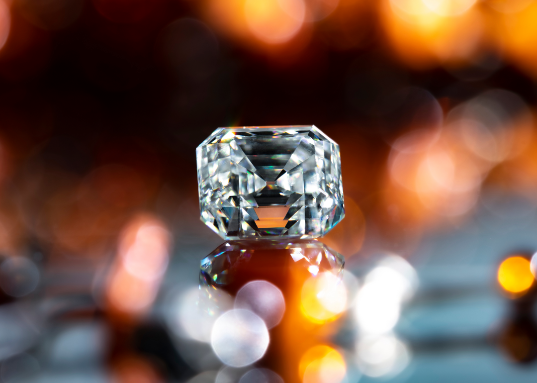 A diamond is displayed against a backdrop of orange and gold lighting.