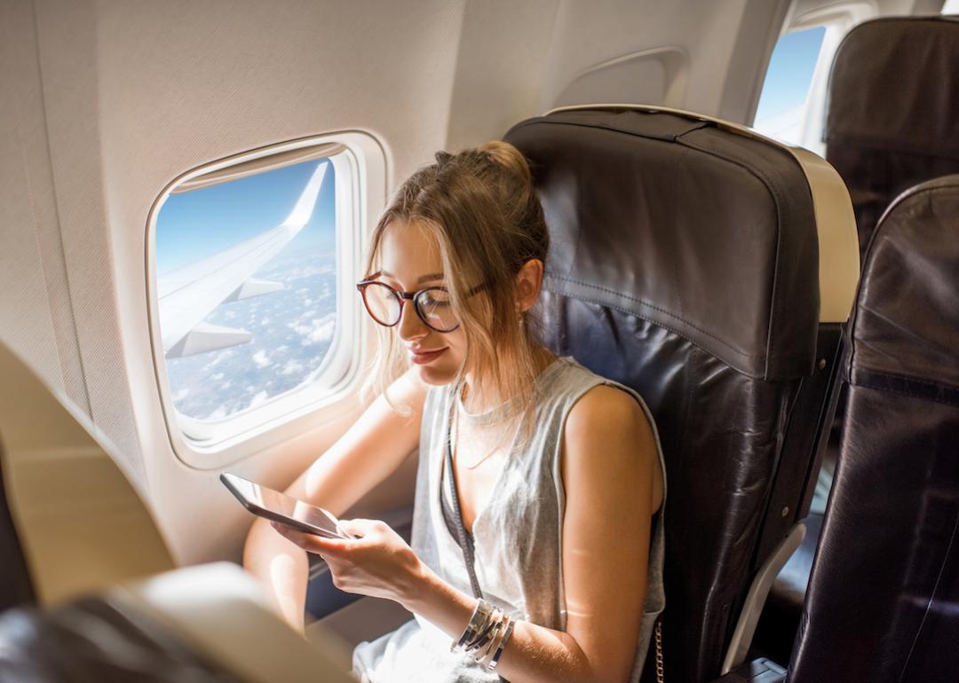 A person holding a phone while seated on an airplane.