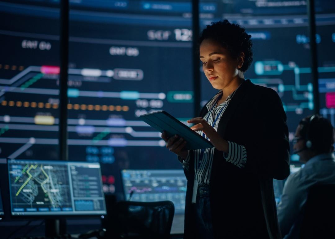 An employee uses a tablet computer in system control monitoring center.