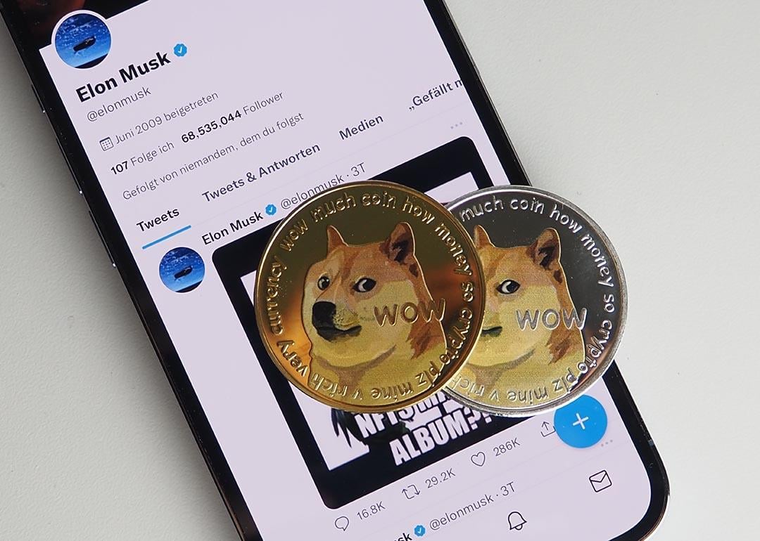 Two DOGE coin displayed on top of a smartphone with Elon Musk twitter profile open.
