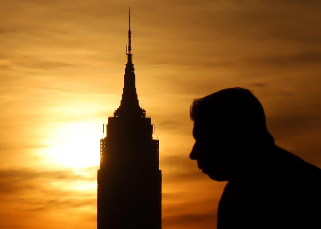 The sun rises behind the Empire State Building as a heatwave continues in New York City on July 24, 2022, as seen from Hoboken, New Jersey.