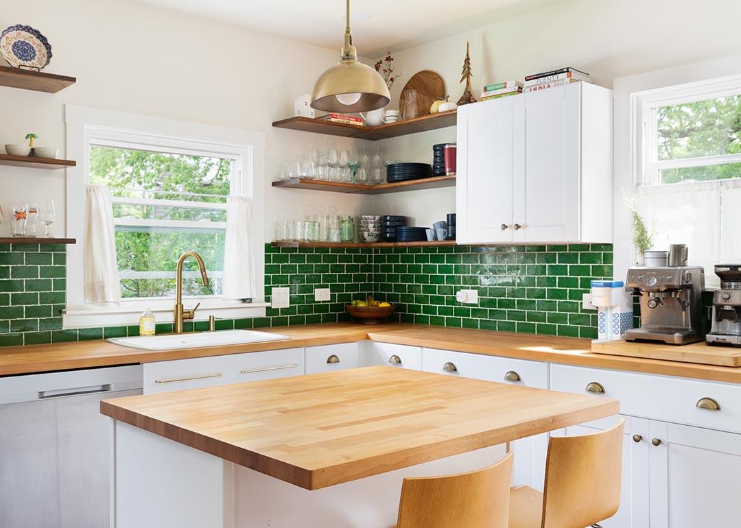 A photo of a remodeled modern kitchen with green, white and wooden interiors and fully furnished.