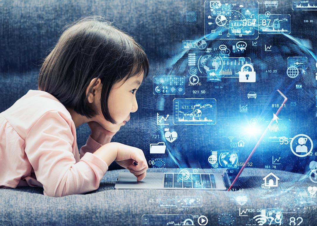 A young girl using a laptop illustrated with holographic internet data and symbols.