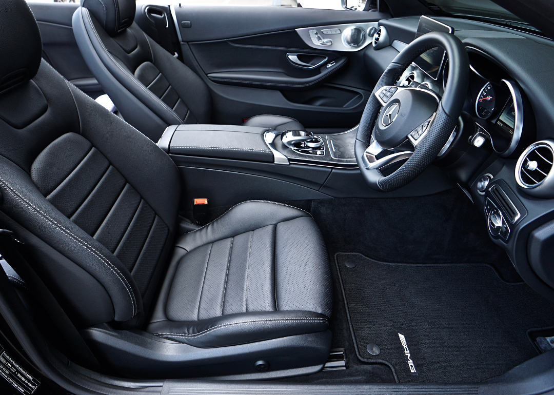 An interior of a modern car showing the dashboard and black leather seats.