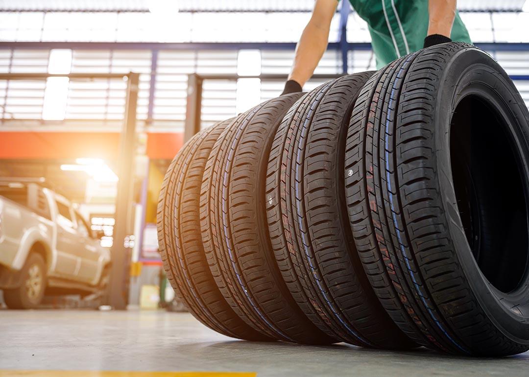 A worker gets a hold of four tires inside a car service establishment.