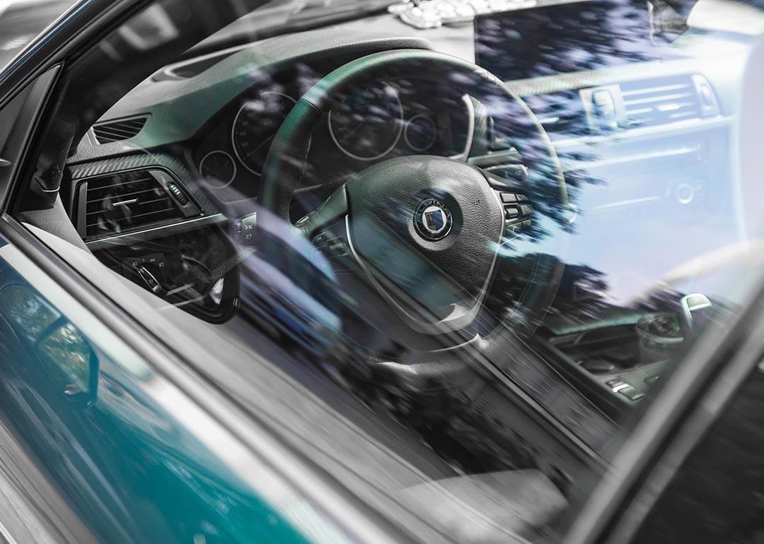 View of steering wheel and dashboard through driver's side window of new vehicle.