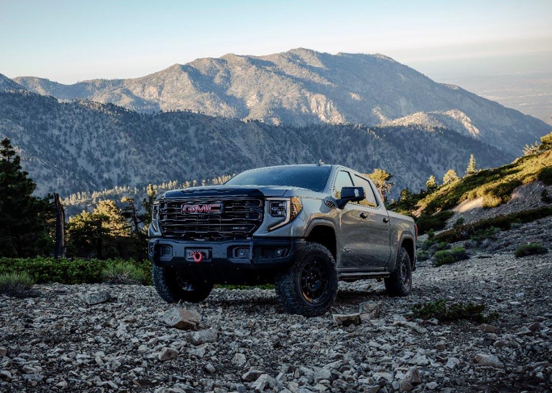 Grey 2023 GMC Sierra 1500 AT4X AEV Edition driving on a rocky hillside.