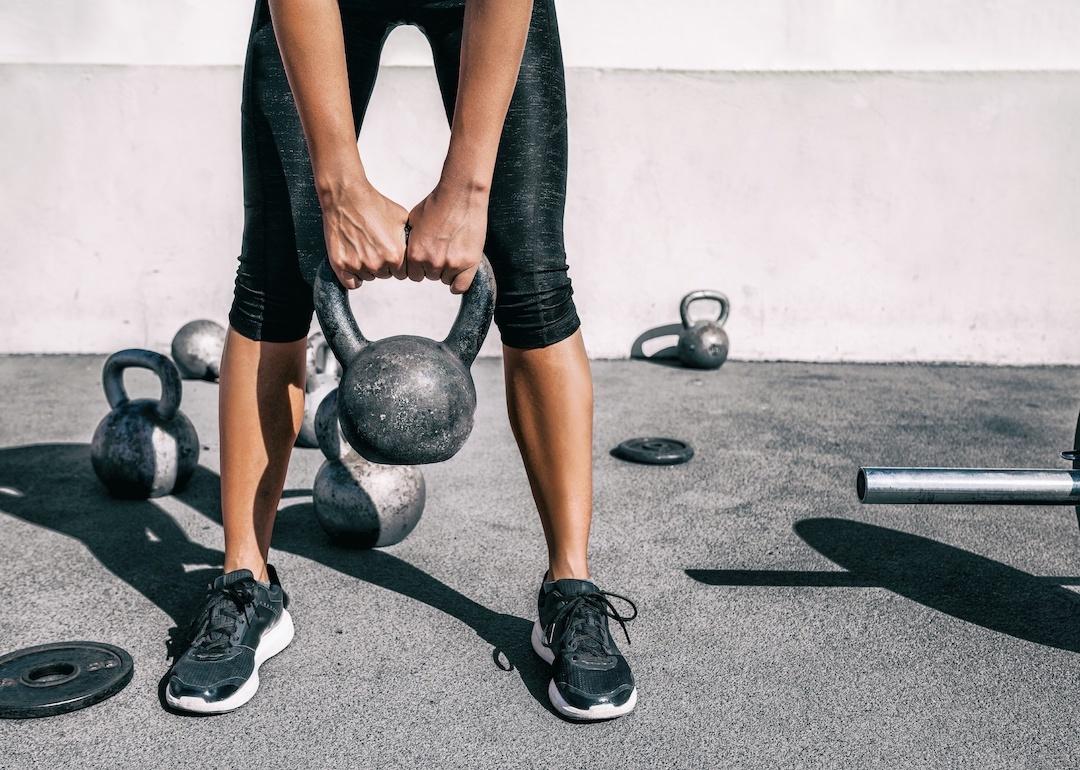 A person lifting a kettlebell weight at an outdoor gym.