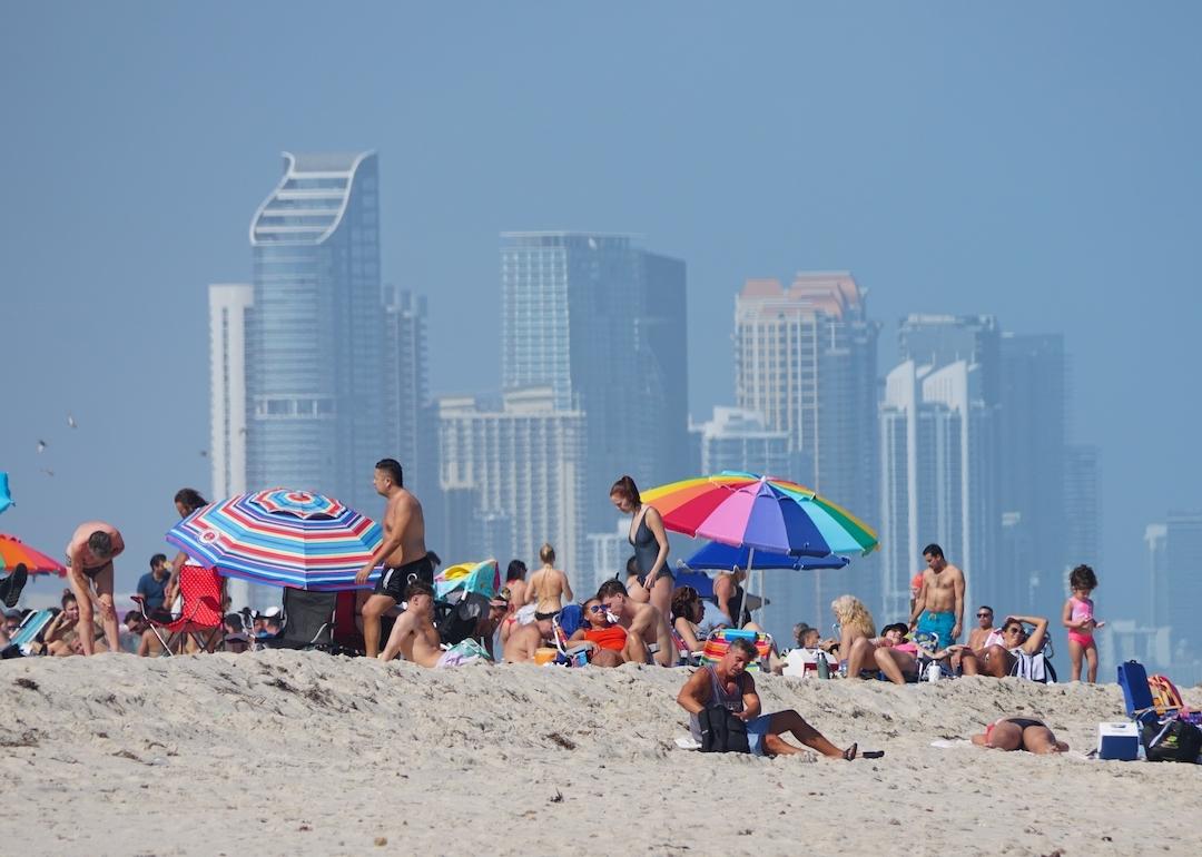 People relaxing on the beach with the skyline of downtown Miami behind them.