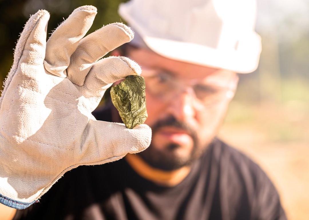 Miner holding gold nugget, with point focus on the gemstone.