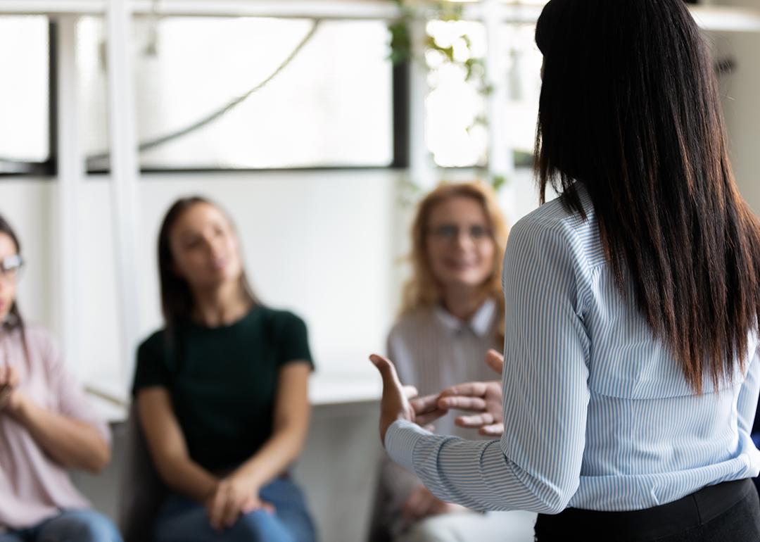 A female counselor facing a group of women and engaging them in a discussion.