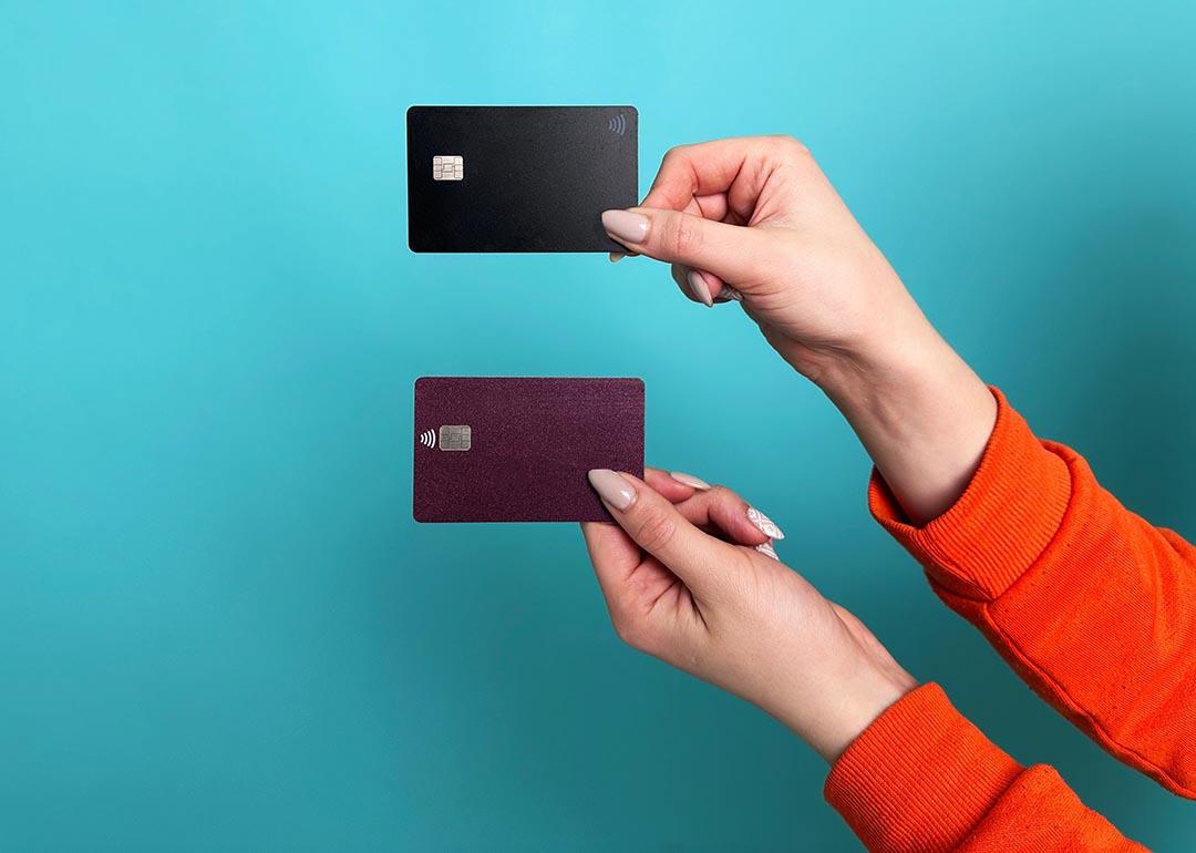 Photo of two hands holding a credit card with each photographed with a teal background.