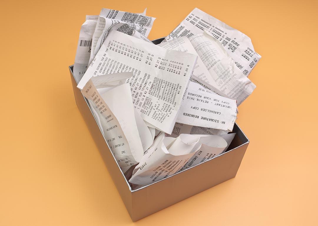 Overflowing box of receipts sitting on orange background.