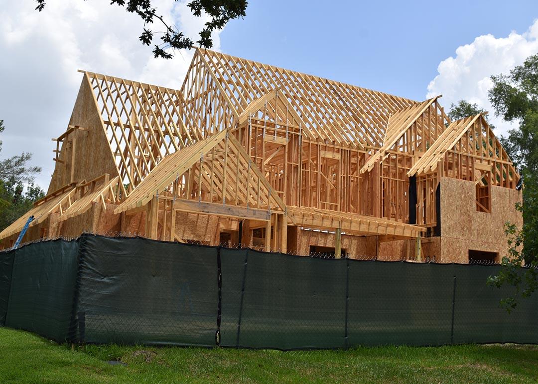 A green fence surrounds the wooden structure of a new home being built in Houston, Texas.