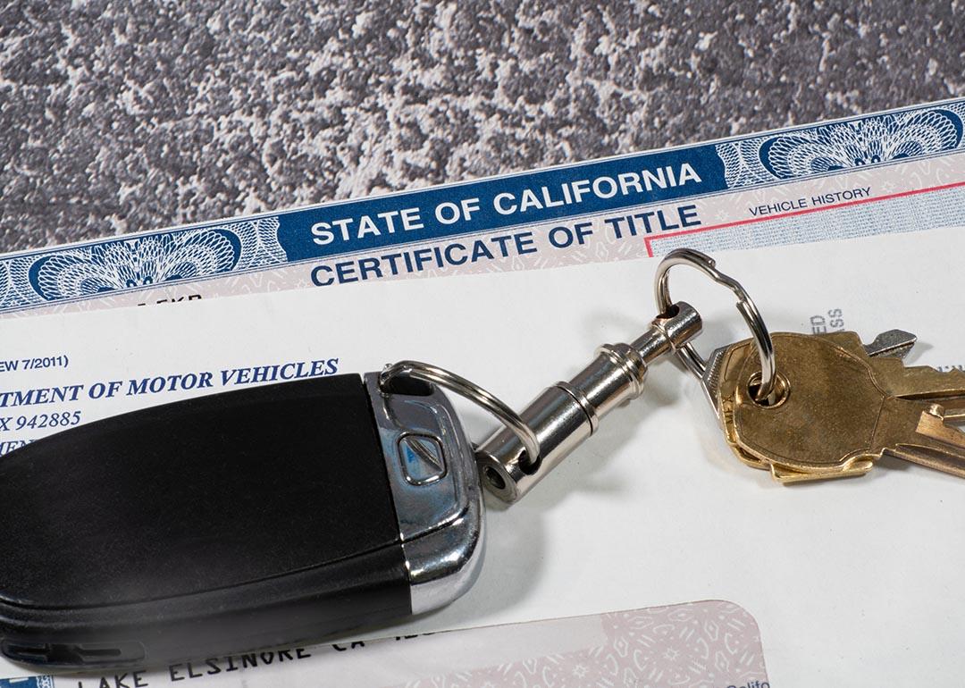 Car keys on top of DMV and certificate of title documents from the State of California.