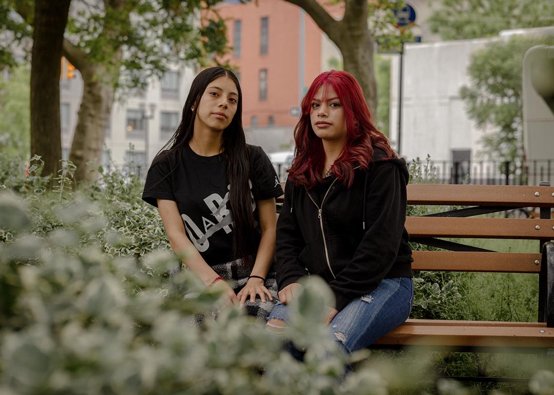 Genesis Callero, 18, and sister Karen Callero, 17, pose for a portrait on a bench surrounded by plants in New York. 