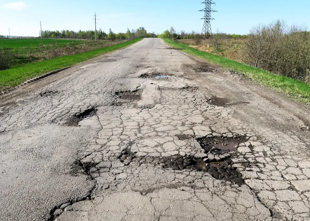 Damaged road with cracked asphalt and potholes