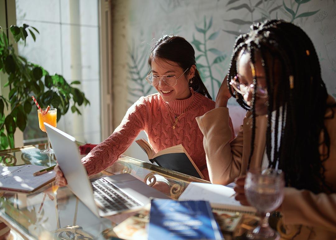 Two Gen Z women are engaged in a discussion while using a laptop.