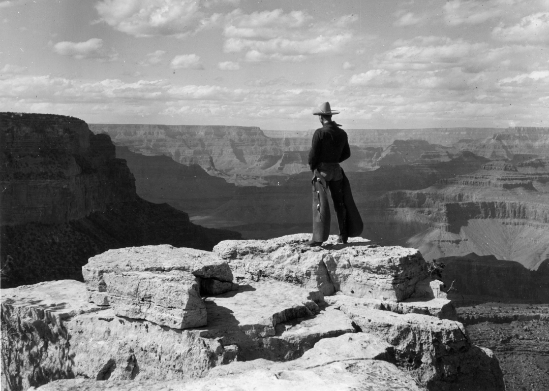 A cowboy wearing chaps stands on Grandeur Point, East Rim Drive, overlooking the Grand Canyon, Arizona, circa 1935. 