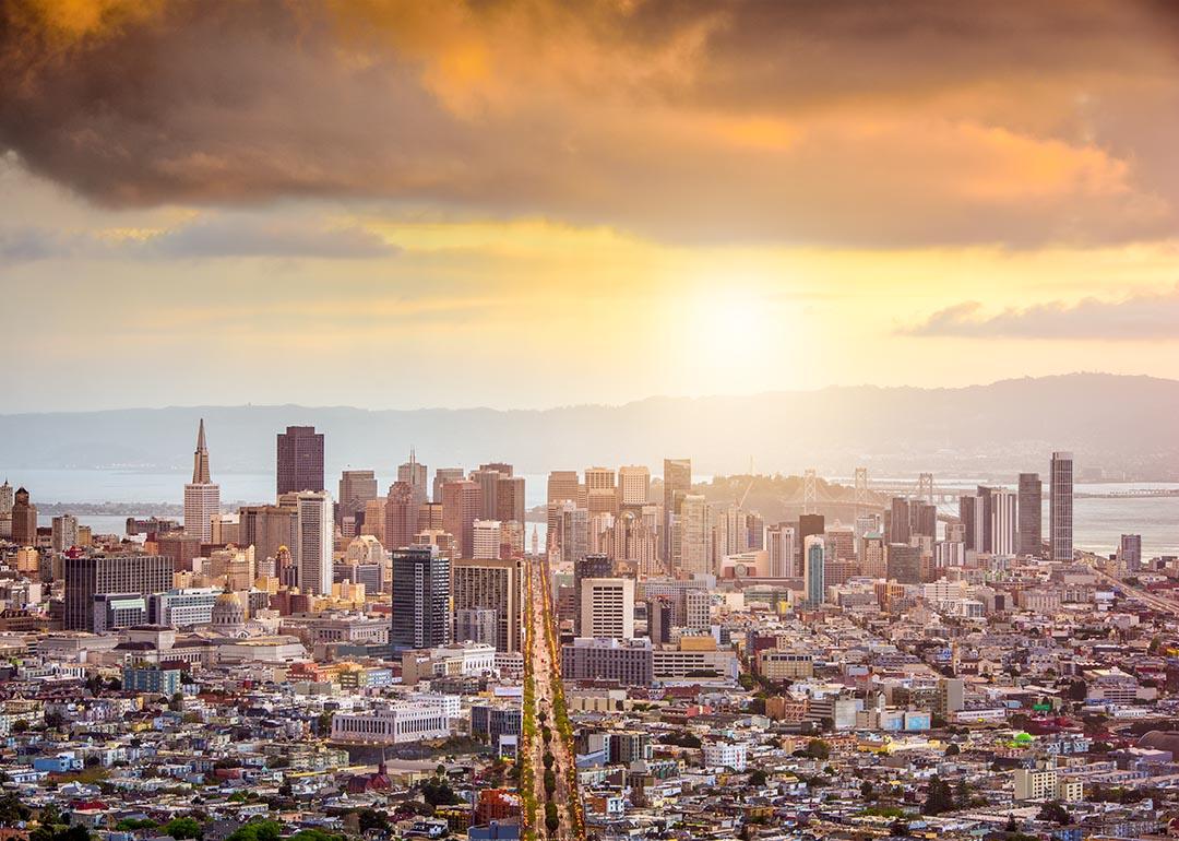 View of San Francisco city skyline at dawn with golden orange clouds above.