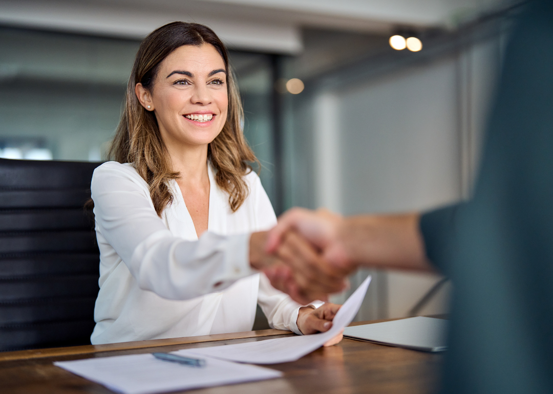 A business manager shaking hands with a potential recruit in an office meeting room