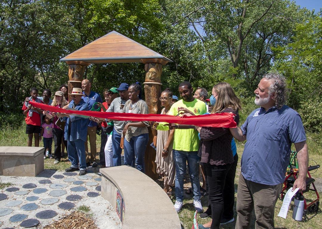 Group photo of members of Imani Village in Chicago holding up a long red ribbon for a ceremony.