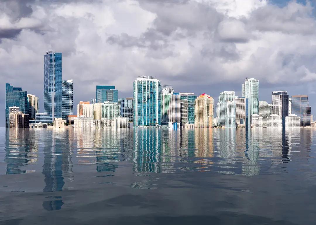 City skyline dots cloudy sky over flooded sea.