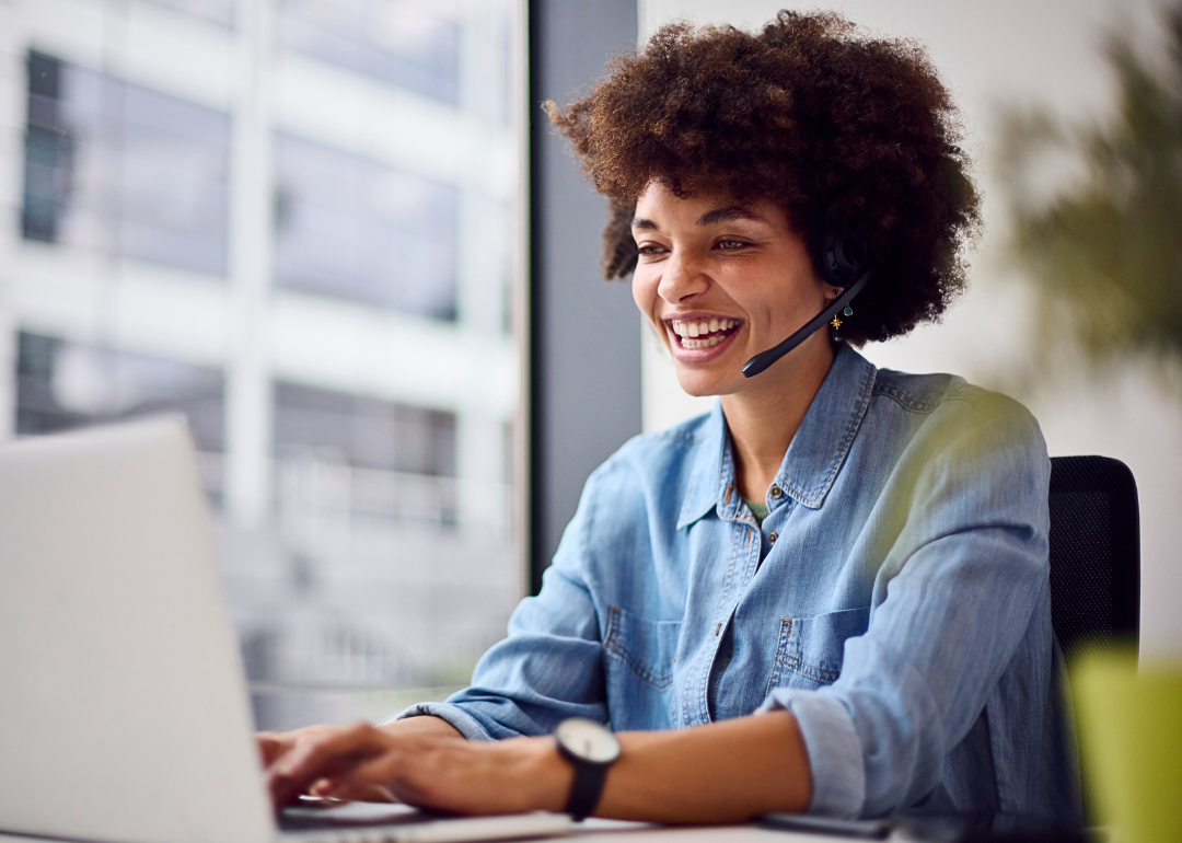 Telemarketer in a blue shirt smiles while on a call.