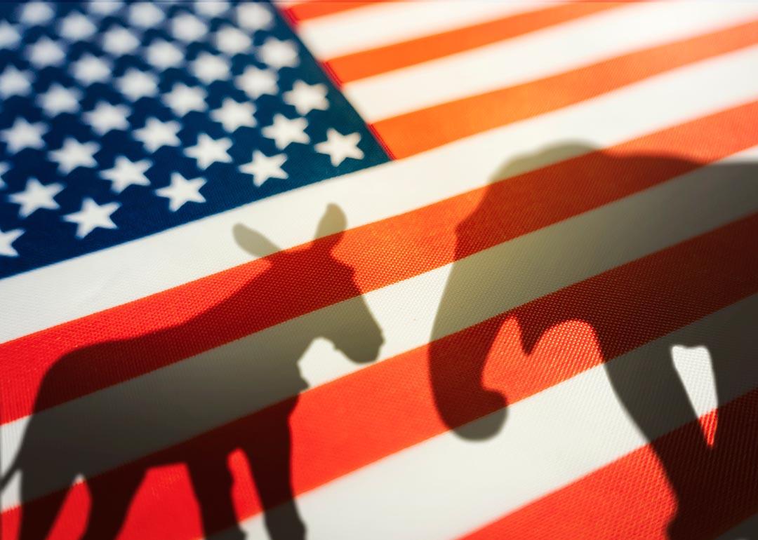 Silhouette of donkey and elephant seen through American flag as concept of Democrats vs Republicans.