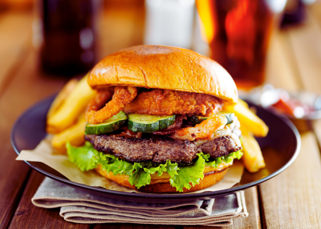 Burger loaded with onion rings and pickles.