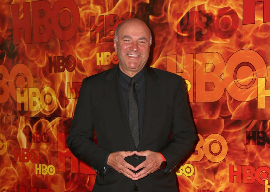 Kevin O'Leary poses in front of a red and orange HBO step-and-repeat background.