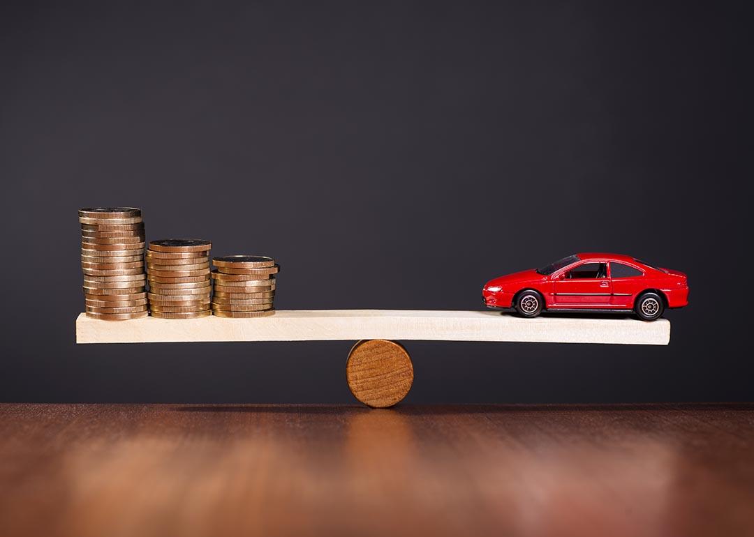 Concept of car value; selling car that is not paid off. illustrated by a seesaw balancing money on one side against a car on the other.