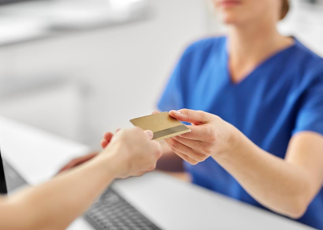 Close up of a person handing a credit card to a pay at a medical office. 