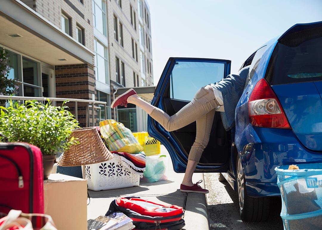 A parent packing their car with items and bags to help with college move-in day.