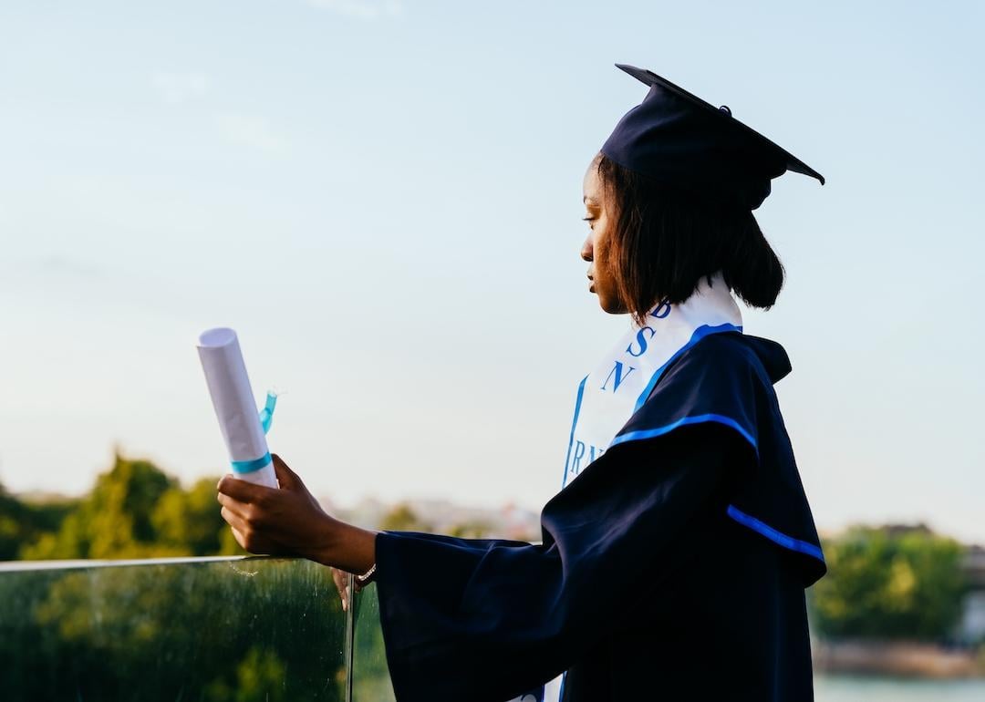 Portrait of college graduate holding a diploma and looking into the distance.