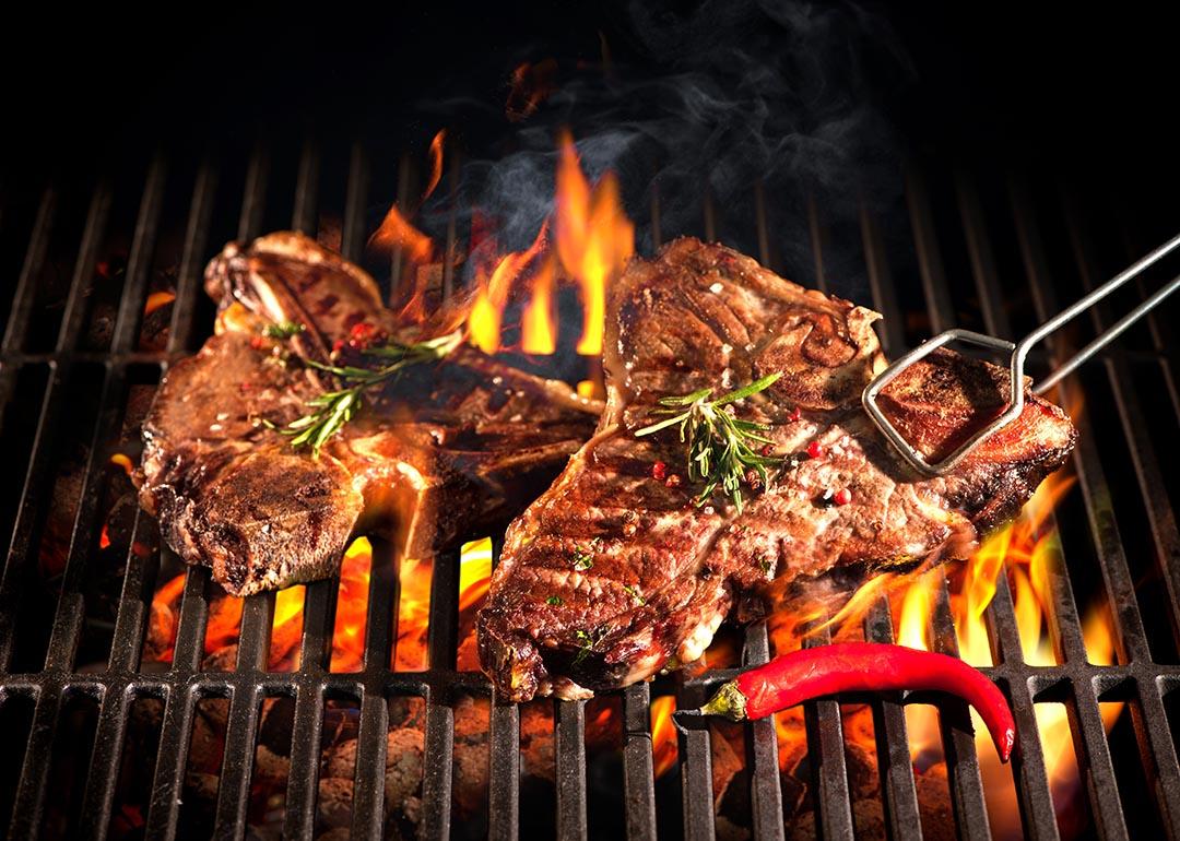 T-bone steak cuts being grilled in open fire.