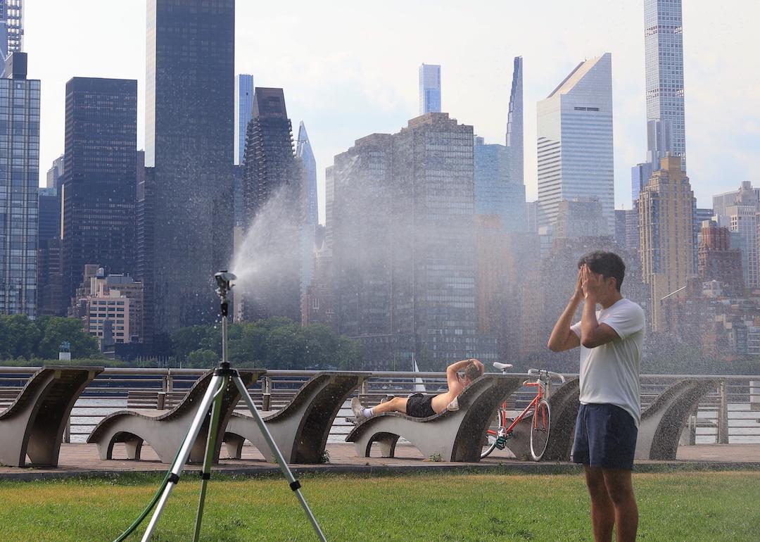 Sprinklers help people cool off during the hot days as temperatures climb to over 100 degrees in Long Island City, New York on June 21, 2024.