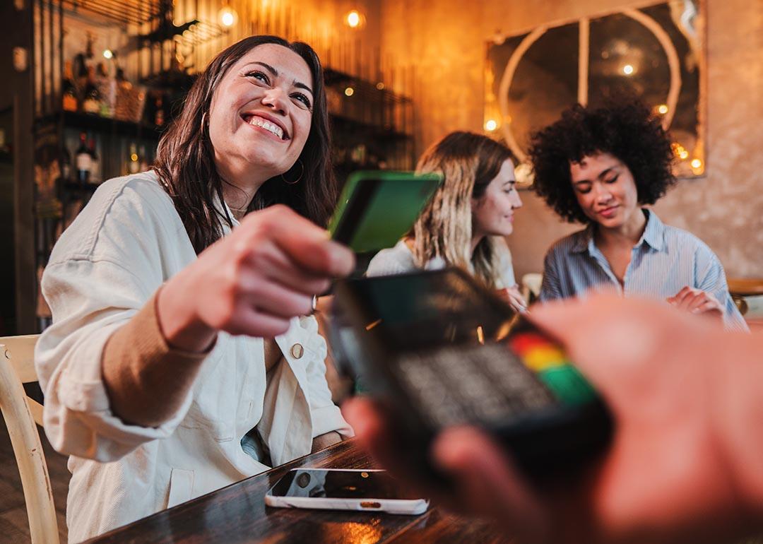 Group of women on a night out while one of them pays with a credit card.