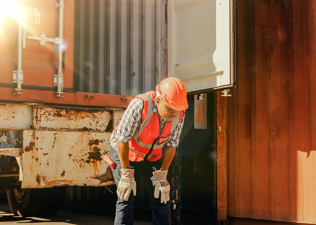 An African-American male container port worker appears tired and dizzy from intense heat.