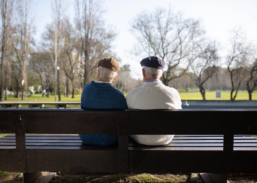 An old couple sittong on a bench park.