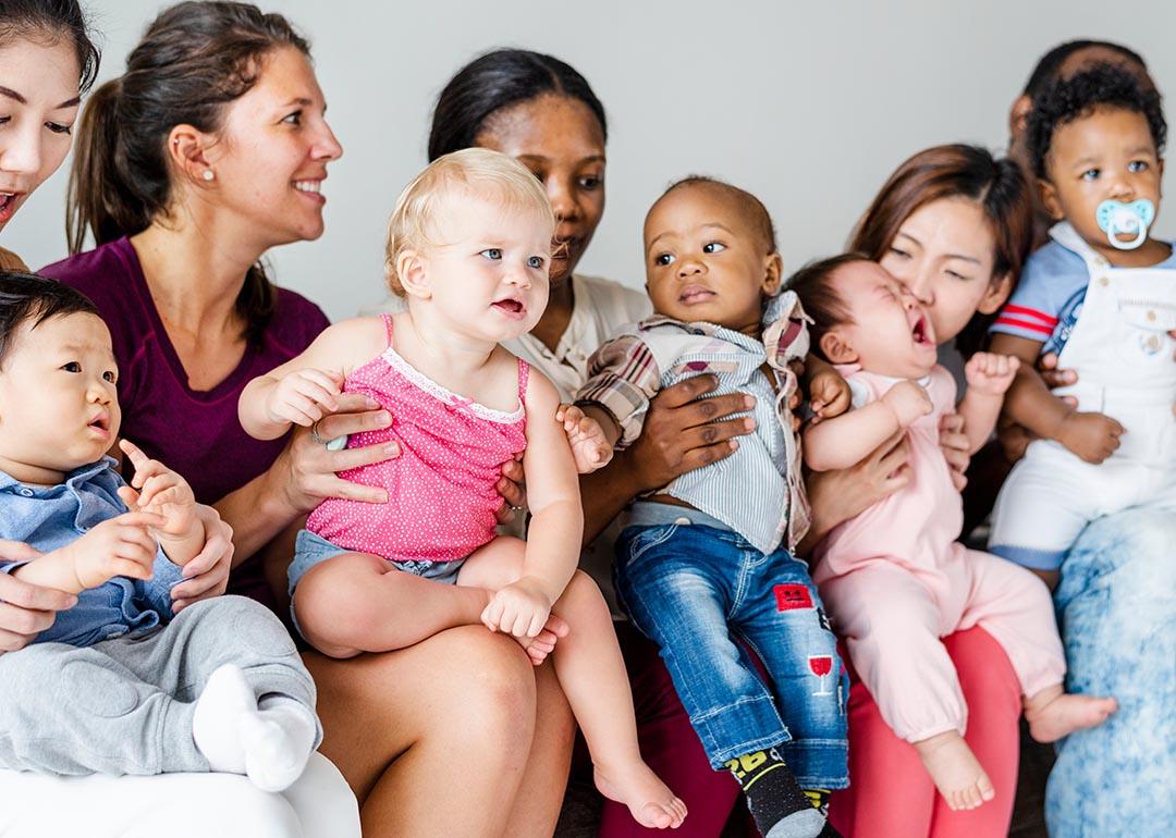 A group of five parents are sat and each one is holding their little child.