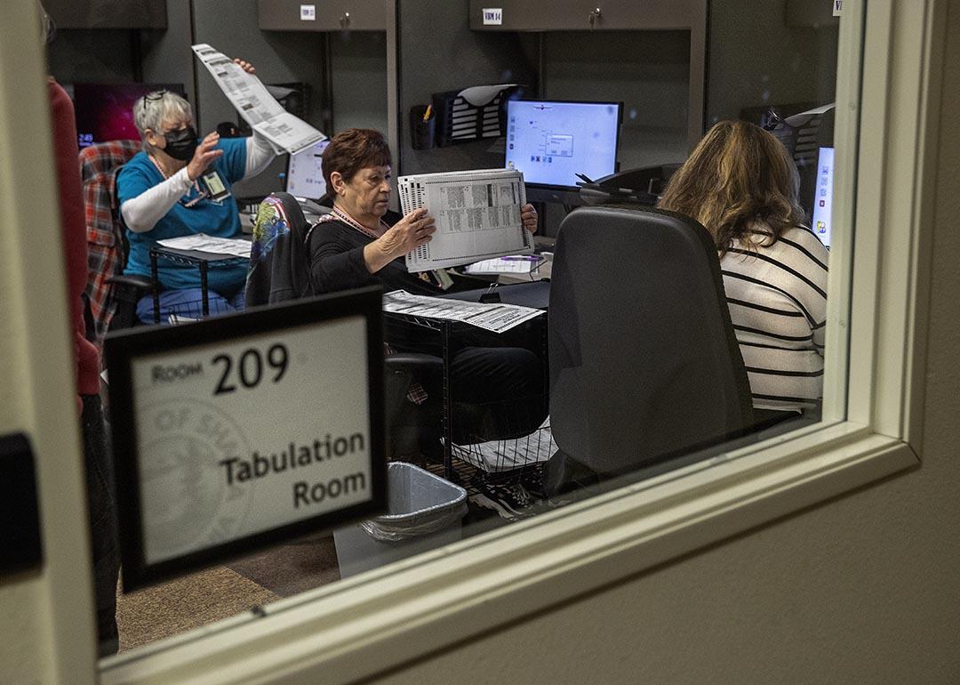 Clerk election specialists prepare to feed ballots into the tabulator/scanner at the Shasta County Clerk & Elections office in Redding in 2022.