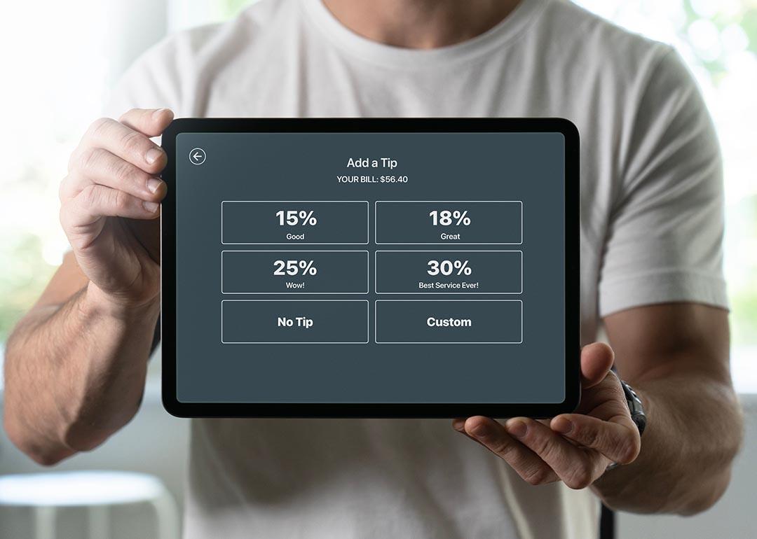 Person holding a tablet displaying an 'add a tip' interface.