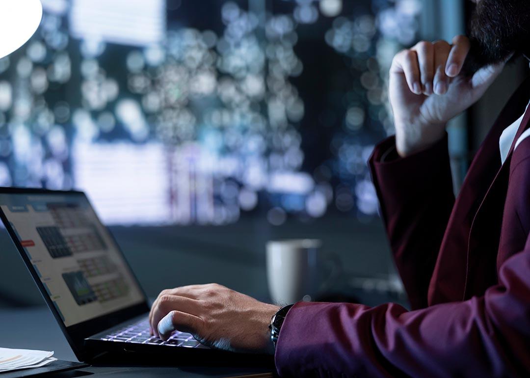 Person looks at finance data on laptop with abstract background suggesting concept of technology and future.